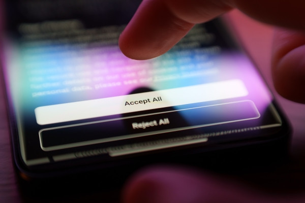 Doigt appuyant sur un bouton 'Accepter tout' sur un écran de smartphone, illustrant le consentement aux cookies et à la gestion des données personnelles.